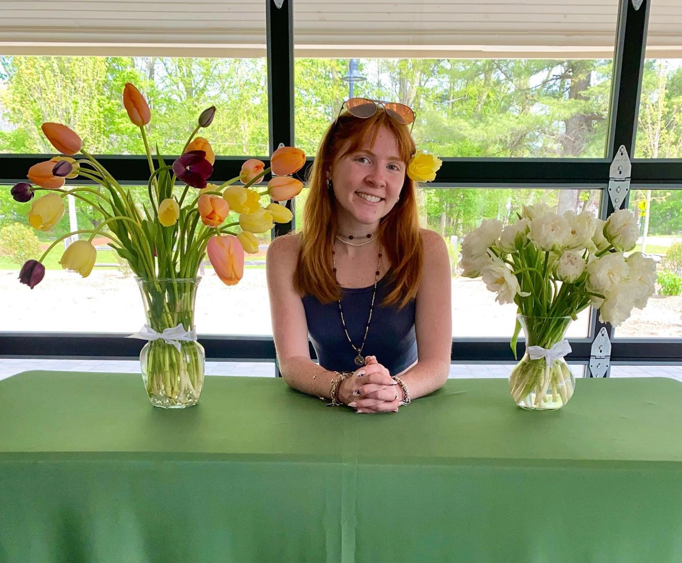 Catherine McGonagle, STEMS Co-Founder & President, sitting at table with two vases of tulips and dahlias